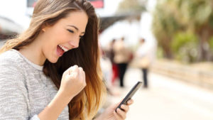 mulher olhando para o celular e comemorando soluções